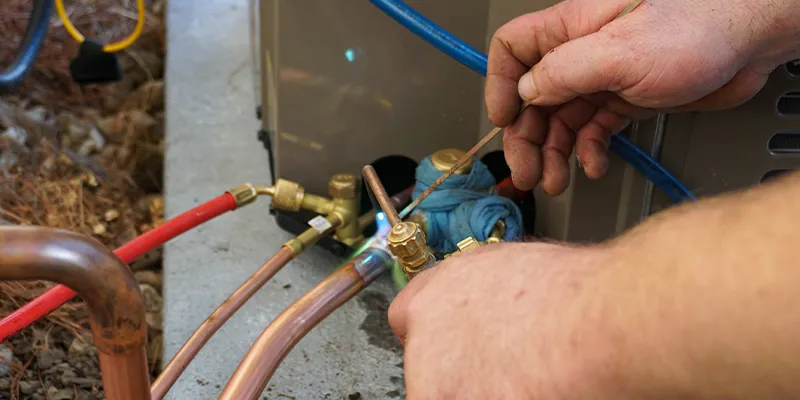 A closeup of an HVAC technician fixing a freon leak