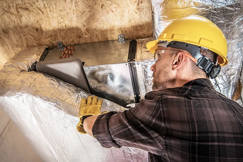 Technician inspecting ductwork for leaks