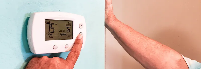 Closeup of hands adjusting a thermostat