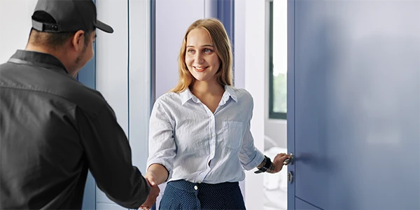 A Bill's Heating ductless heat pump expert technician is shaking hand with a woman at the front door to her home.