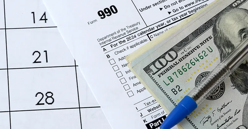 A tax form with 100 dolar bills stacked next to it