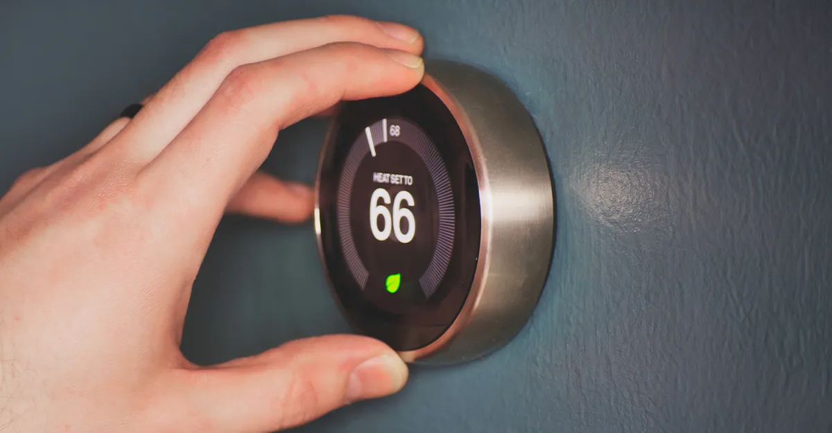 Hand adjusting a modern smart thermostat on the wall