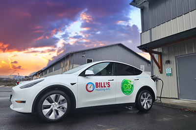 A Tesla with Bills Heating graphics is plugged into a Chargepoint EV charger.