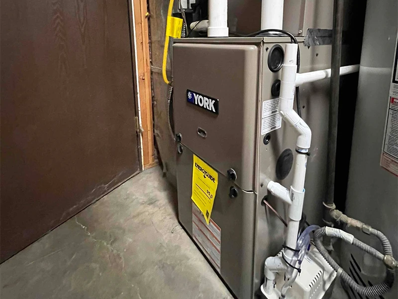 A side shot of a quality furnace install that showcases the complex drain piping and Bills Heating and AC's professionalism.