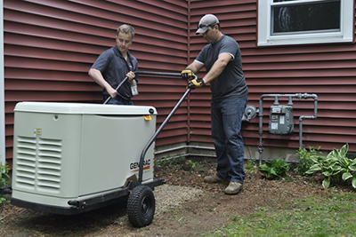 An electrician and plumber from Bill's Heating and AC setting a Generac Generator in place.