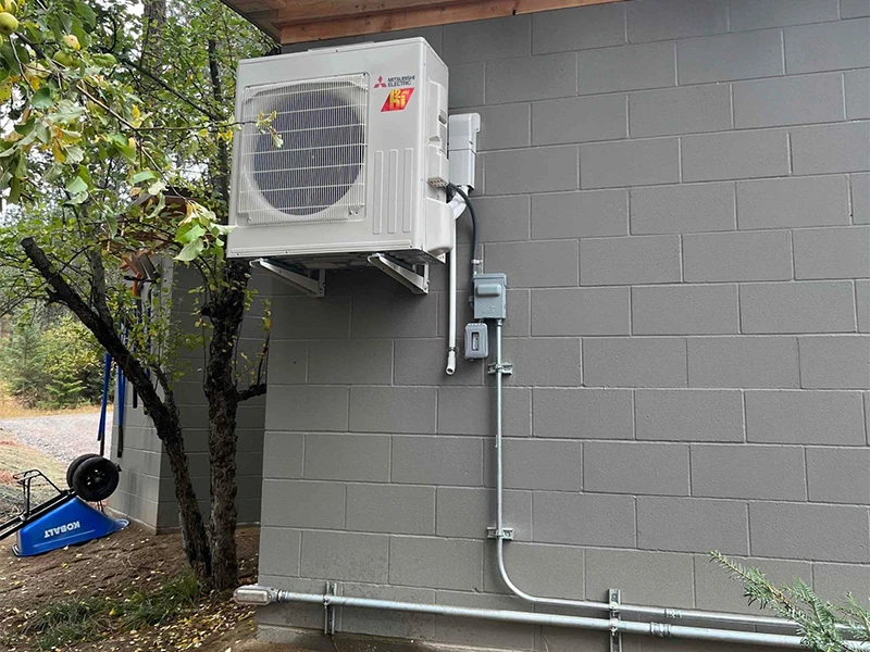 A Mitsubishi Ductless condenser from their hyper-heat line, mounted on an exterior wall of a building.