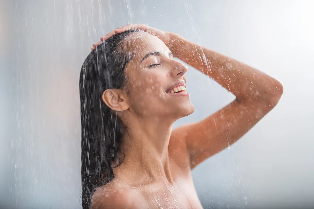 a woman smiles while taking a shower